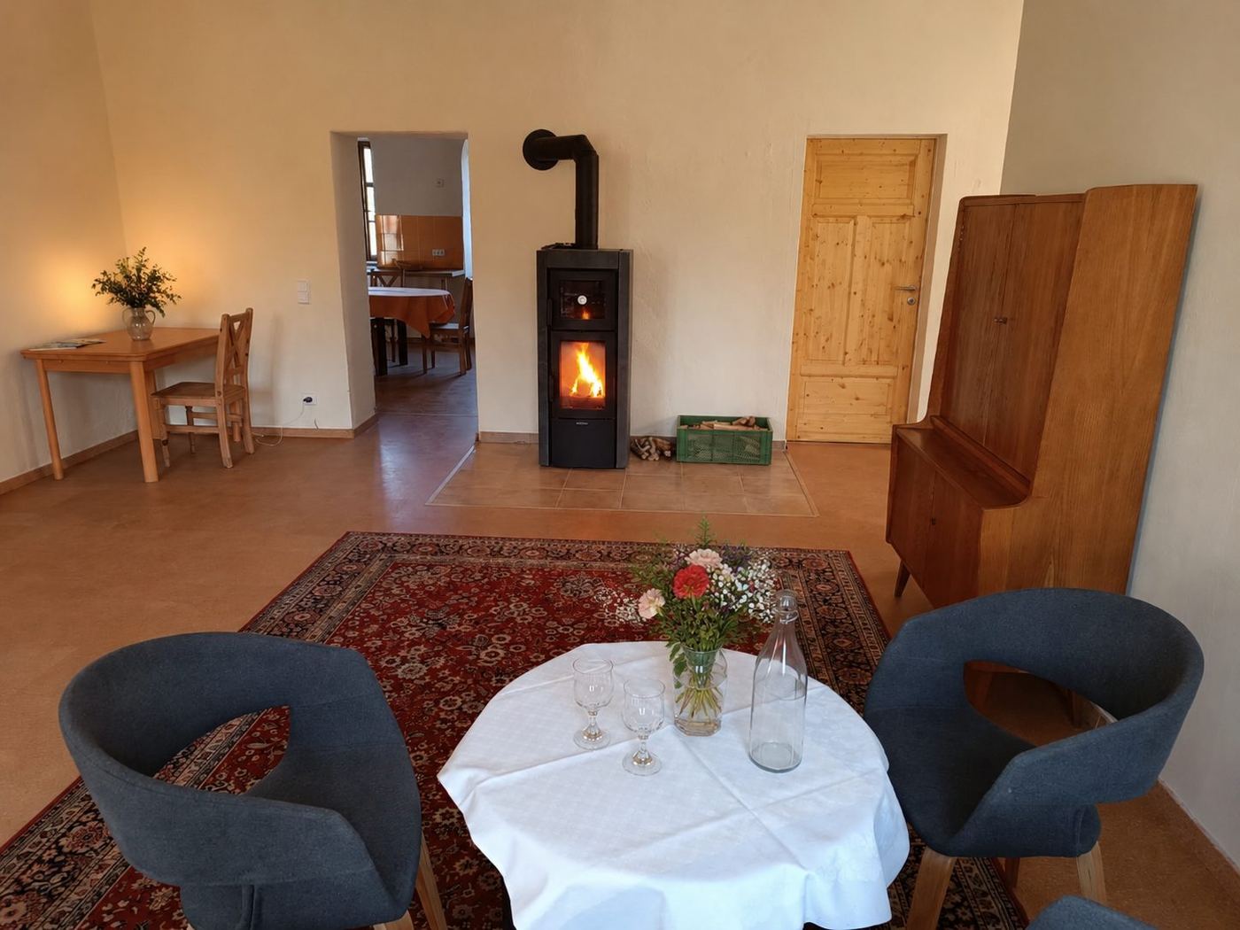 Wohnbereich der Ferienwohnung mit Kaminofen, gedecktem Tisch und antiken Möbeln