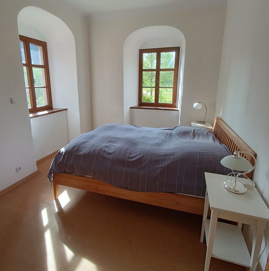 Schlafzimmer mit Doppelbett und Rundbogenfenstern