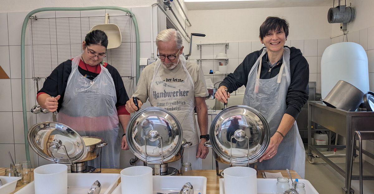 Drei Teilnehmende bei einem Käsekurs in der Hofkäserei von Hofgut Pulsitz, jeweils mit Käsekessel und Käseform